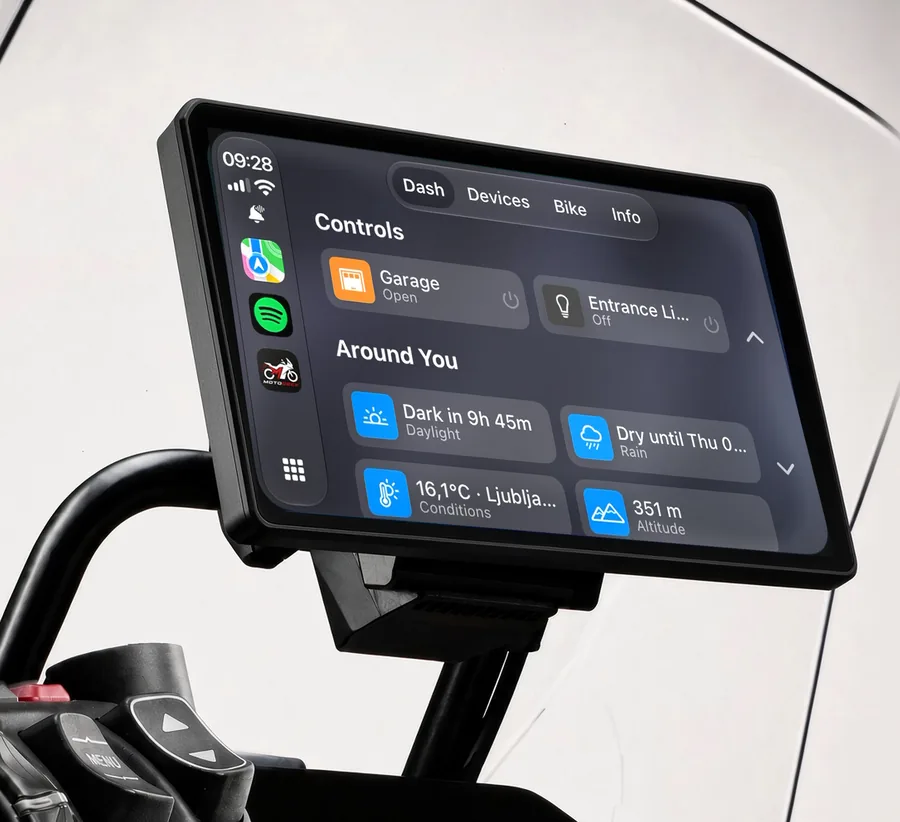 A CarPlay head unit on the bars of a BMW GS, showing the MotoDeck dashboard: garage control, daylight left, rain timing, temperature and altitude.